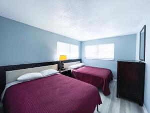 - 2 lits dans une chambre aux murs bleus dans l'établissement Sunrise Resort Motel South, à Clearwater Beach