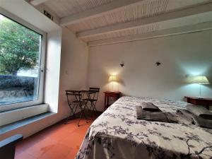 a bedroom with a bed and a window and a table at Casa São Miguel in São Roque do Pico
