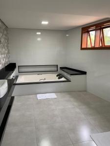 a bathroom with a bath tub and a sink at Katuny Pousada e Eventos in São Domingos do Prata