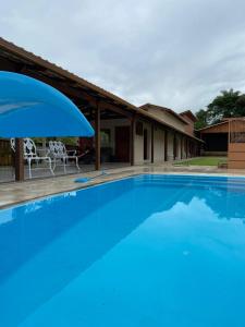 a large blue swimming pool with a house at Katuny Pousada e Eventos in São Domingos do Prata