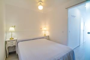 biała sypialnia z łóżkiem i dwiema lampami w obiekcie Neues Apartment am Strand w mieście Arguineguín