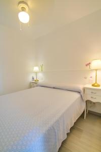 biała sypialnia z białym łóżkiem i 2 lampami w obiekcie Neues Apartment am Strand w mieście Arguineguín
