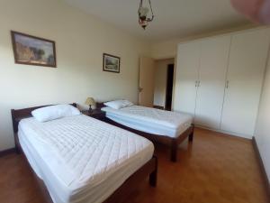 2 camas en una habitación con paredes y armarios blancos en Amplo e Central Apartamento 3 Quartos, en Gramado