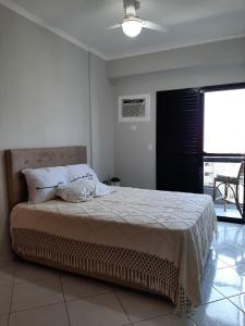 um quarto com uma cama e uma ventoinha de tecto em Apartamento 3 Dormitórios / Praia Enseada Guarujá, Piscina, Vista ao fundo e sol da manhã!. no Guarujá