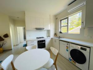 Una cocina blanca con una mesa y sillas blancas. en Lotus Stay Manly - Apartment 29A, en Sídney