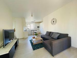 Una sala de estar con un sofá y un reloj en la pared. en Lotus Stay Manly - Apartment 29A, en Sídney