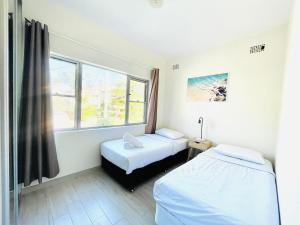 Una habitación de hospital con dos camas y una ventana. en Lotus Stay Manly - Apartment 29A, en Sídney