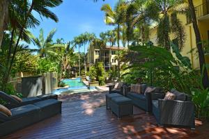 a patio with couches and a pool and palm trees at Reef Club Resort in Port Douglas