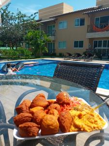 een bord eten op een tafel naast een zwembad bij Guarajuba! Excelente localização, Lindo, confortável e decorado! in Guarajuba