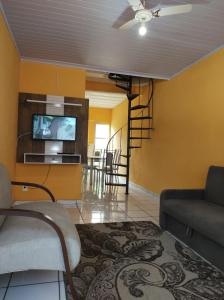 uma sala de estar com um sofá e uma televisão em Apartamento Dulplex Diária/Temporada em Angra dos Reis