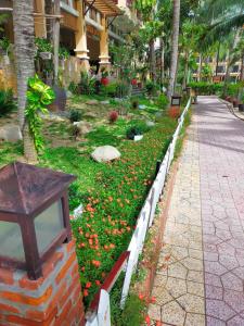 a garden with flowers and a sidewalk next to a building at Hon Rom Central Beach Resort in Mui Ne