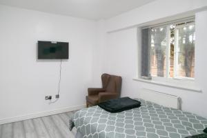 a bedroom with a bed and a chair and a television at Hills View Apartments in Manchester