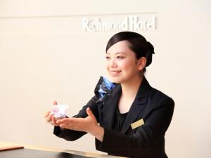 una mujer parada frente a una mesa sosteniendo una botella en Richmond Hotel Fukushima Ekimae, en Fukushima