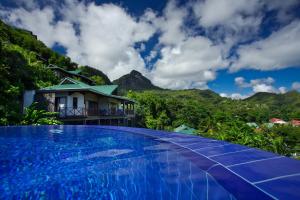 una piscina frente a una casa con montaña en Villas de Jardin self-catering en Port Glaud