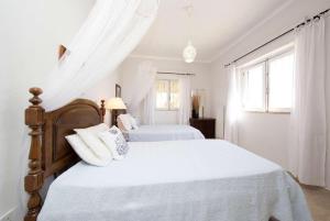 BordeiraにあるJacarandaの白いカーテン付きの白いベッドルームのベッド2台