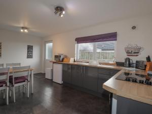 a kitchen with a counter and a table and a window at Lilac Cottage in Strathpeffer