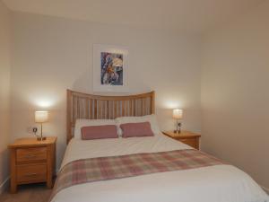 een slaapkamer met een groot bed met 2 nachtkastjes bij Lilac Cottage in Strathpeffer