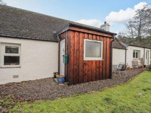 a wooden shed in the backyard of a house at Lilac Cottage in Strathpeffer
