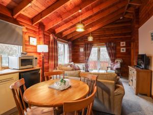a kitchen and living room with a table and chairs at Spruce Lodge in Strathpeffer