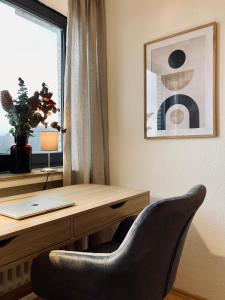 a desk with a laptop and a chair next to a window at Schickes, Stilvolles und Helles Apartment in Münster in Münster