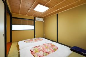 two beds in a room with a ceiling at Rinn Fushimiinari in Kyoto