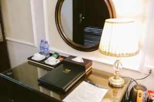 a desk with a lamp and a book and a mirror at Vincent Halong Hotel in Ha Long