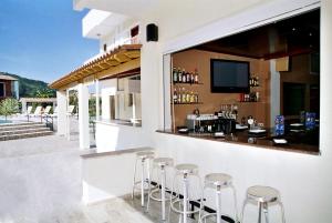a bar on the side of a building with stools at Hotel Prassino Nissi in Moraitika