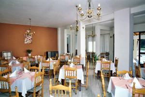 a dining room with tables and chairs and a chandelier at Hotel Prassino Nissi in Moraitika