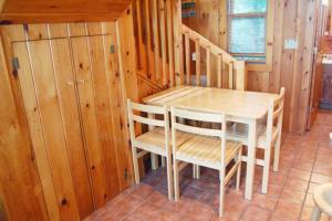 una mesa y sillas en una habitación con paredes de madera en Loons Nest Cottage, en Standish