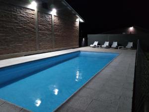 una piscina por la noche con sillas alrededor en Cabañas Quimera en Santa Rosa de Calamuchita