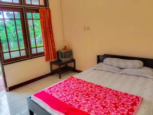 a bedroom with a bed with a red blanket at Nguntara Gati in Sleman