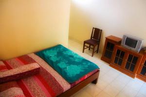 Schlafzimmer mit einem Bett, einem TV und einem Stuhl in der Unterkunft Nguntara Gati in Sleman