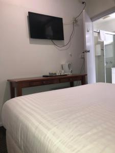 um quarto de hotel com uma cama e uma televisão na parede em Evancourt Motel Malvern East em Melbourne