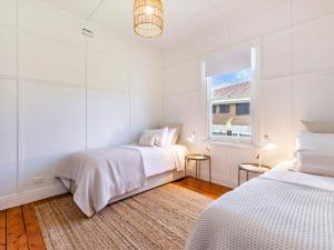 ein weißes Schlafzimmer mit 2 Betten und einem Fenster in der Unterkunft The Anchor House in Port Fairy