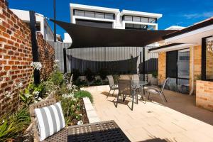 un patio con mesa y sillas y un edificio en Scarborough Villa on Duke - EXECUTIVE ESCAPES, en Perth