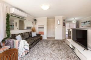 een woonkamer met een bank en een flatscreen-tv bij Scarborough Villa on Duke - EXECUTIVE ESCAPES in Perth