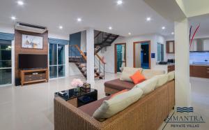 a living room with a couch and a tv at Simantra Private Villas in Cha Am