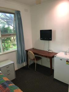 a room with a desk and a tv on the wall at Evancourt Motel Malvern East in Melbourne