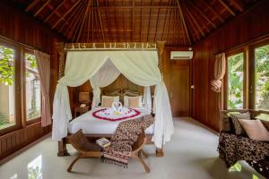 a bedroom with a white bed with a canopy at Nur Guest House by Purely in Ubud