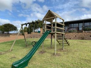 a playground with a green slide in a yard at Outeniquabosch Lodge in Hartenbos