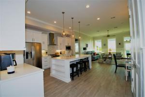cocina y sala de estar con armarios blancos y mesa en Anchors Aweigh cottage, en South Padre Island