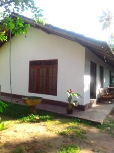 a white house with a red door and a yard at Sugaya in Matara