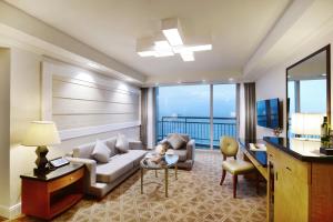 a living room with a couch and a table at Ramada Plaza by Wyndham Jeju Ocean Front in Jeju