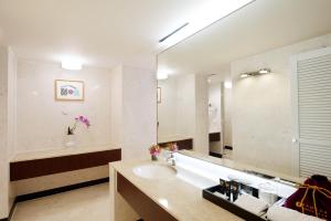 a bathroom with a sink, mirror, and bathtub at Ramada Plaza by Wyndham Jeju Ocean Front in Jeju