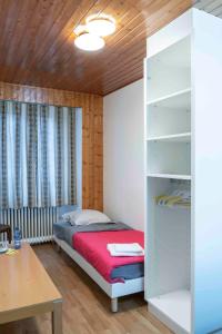 mała sypialnia z łóżkiem i biurkiem w obiekcie Hôtel du Cheval-Blanc w mieście La Chaux-de-Fonds