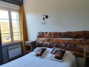 a bedroom with a wooden headboard with two pillows on a bed at Grand Hotel de la Vallée in Cheylade