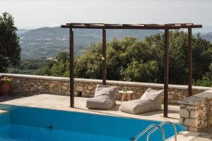 una piscina con cuscini e pergolato accanto a una piscina di Koules Estate, simplicity & natural, By ThinkVilla a Argoulión