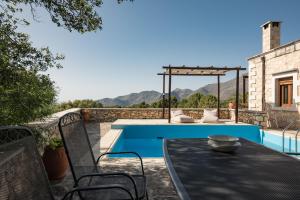 un patio con mesa y sillas junto a una piscina en Koules Estate, simplicity & natural, By ThinkVilla en Argoulión