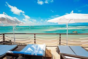 einen Strand mit Liegestühlen und Sonnenschirmen und dem Meer in der Unterkunft Boutique Hotel Marlin's in Pipa