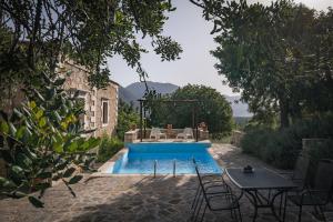 a pool with a table and chairs next to a house at Koules Estate, with Private Pools & BBQ - embracing Nature, By ThinkVilla in Argoulión